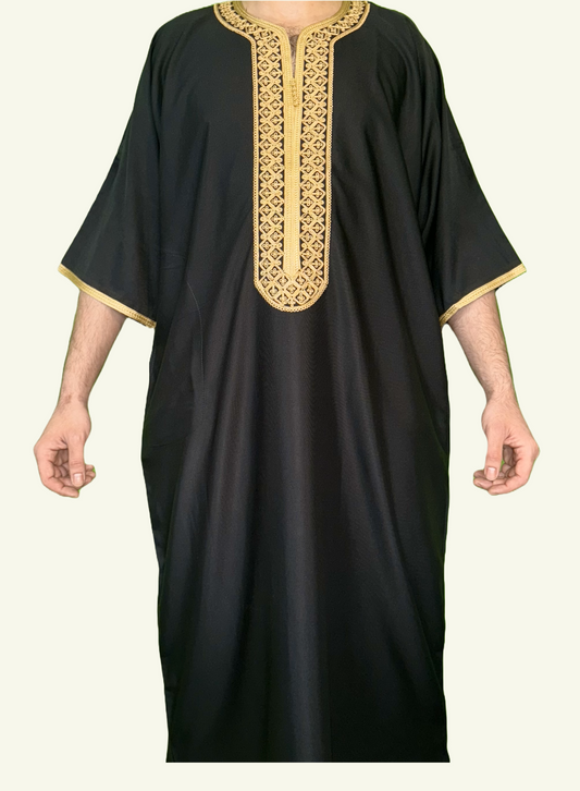 Ein stilvoller Körper, auf dem eine Djellaba Noble in schwarz liegt, ein Symbol für Eleganz und Tradition. Das Strickmuster auf der Brust und die Enden der Ärmel sind mit goldenem Strick verziert.