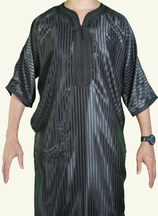 Ein männlicher Körper in einem gestreiften schwarzen Djellaba-Gebetskleid. Der Kopf und die Füße sind nicht sichtbar. Das Kleid zeichnet sich durch seine lockere und legere Passform aus.